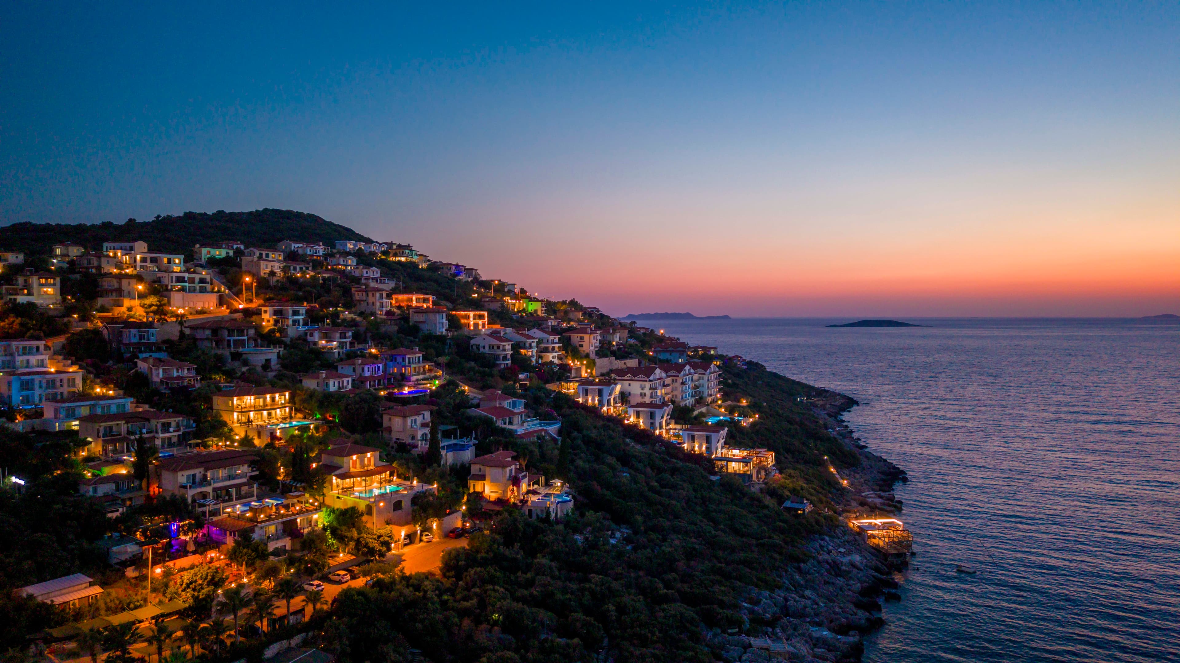 The Kaş peninsula coastline at twilight, hillside villas lit up above the bay