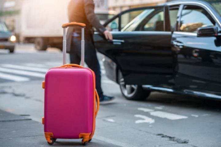 Luggage waiting beside a private transfer vehicle with the door open