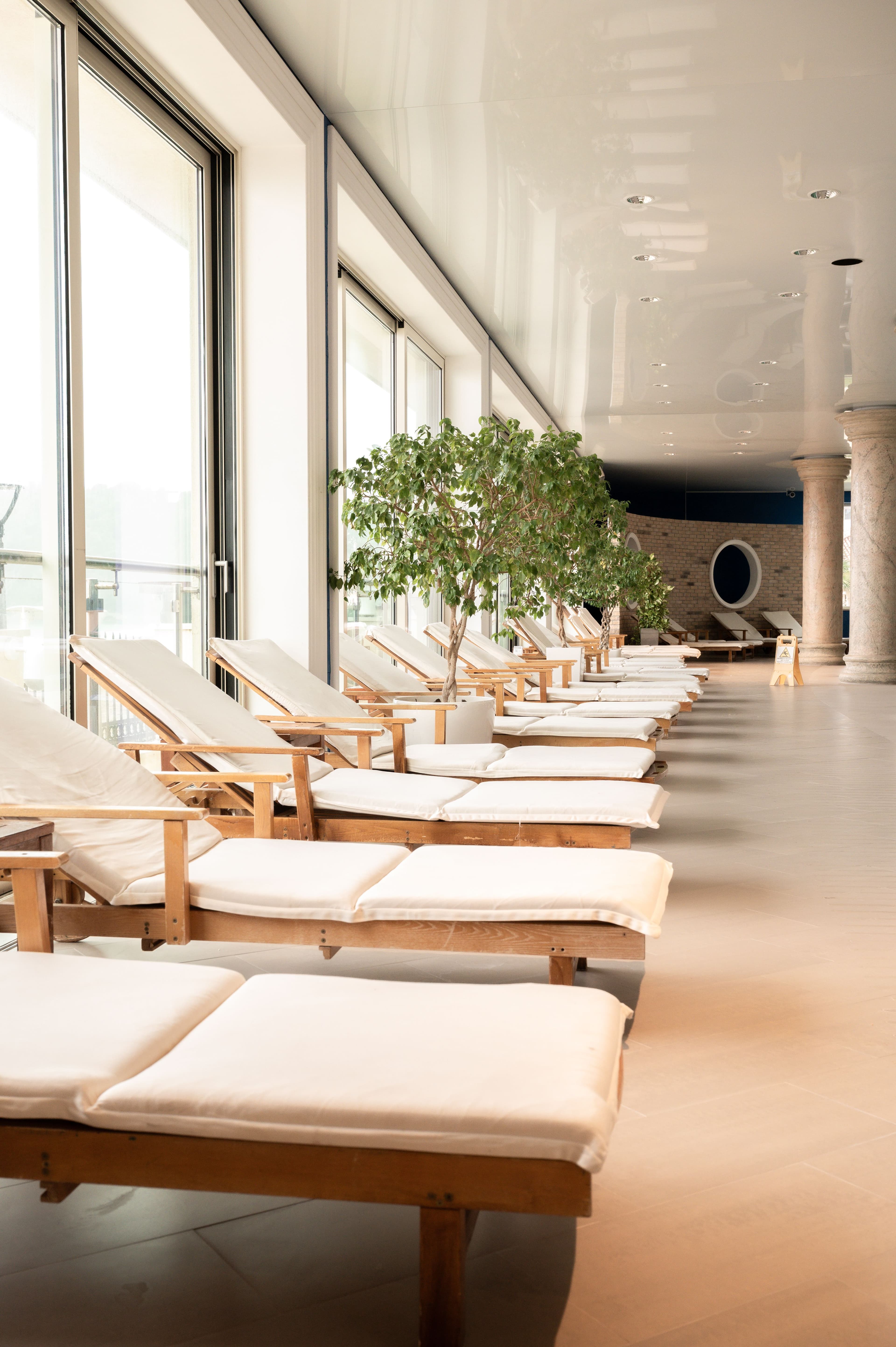 A row of lounge chairs along a sunlit window in a quiet spa relaxation area